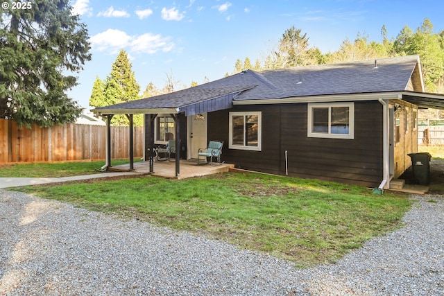 back of property featuring a lawn, a patio, a fenced backyard, and roof with shingles