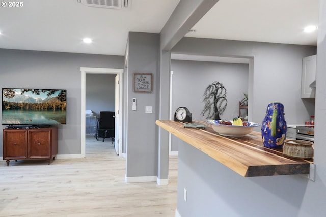 kitchen with stove, butcher block countertops, and light hardwood / wood-style floors