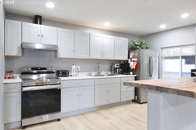 kitchen featuring a sink, light wood-style floors, wood counters, stainless steel appliances, and under cabinet range hood