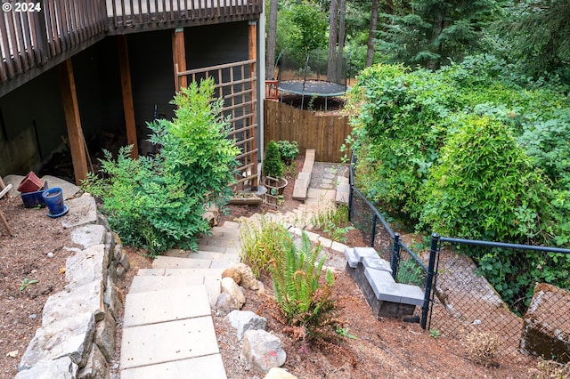 view of yard featuring a trampoline and a wooden deck