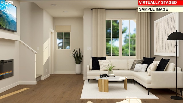 living room with a glass covered fireplace, baseboards, and wood-type flooring