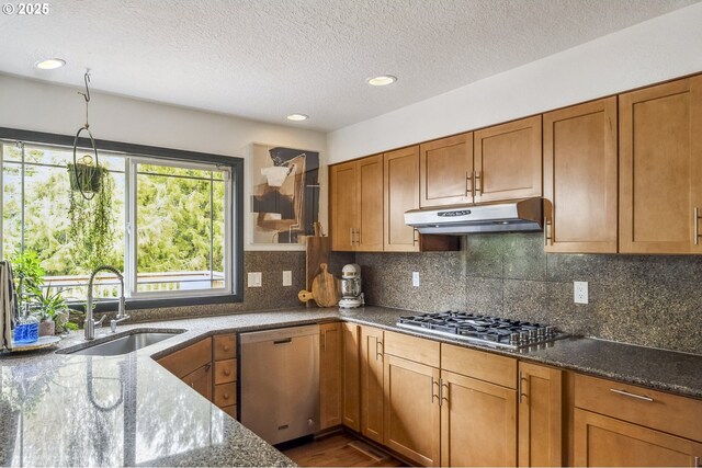 kitchen featuring sink, gas stovetop, stainless steel dishwasher, and dark stone counters