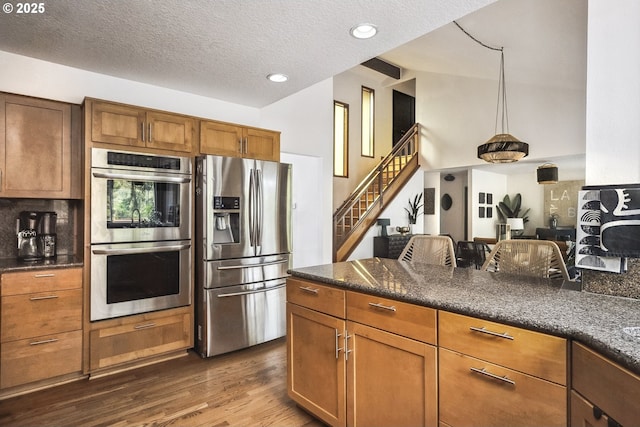 kitchen featuring dark wood-type flooring, tasteful backsplash, vaulted ceiling, a textured ceiling, and stainless steel appliances