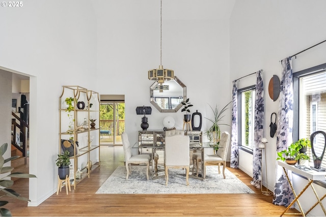 dining area with a towering ceiling and light hardwood / wood-style floors