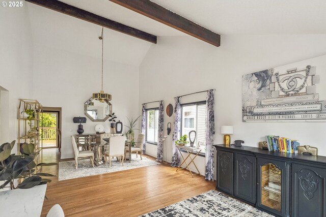 dining room with light hardwood / wood-style floors and vaulted ceiling with beams