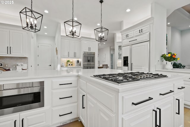 kitchen featuring decorative light fixtures, white cabinets, ornamental molding, and appliances with stainless steel finishes