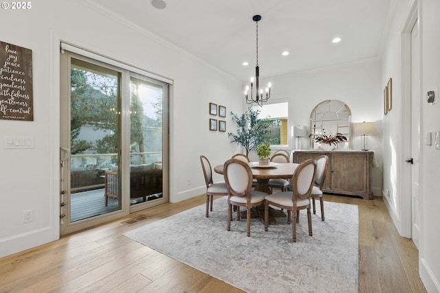 dining space featuring light wood-type flooring, an inviting chandelier, and crown molding