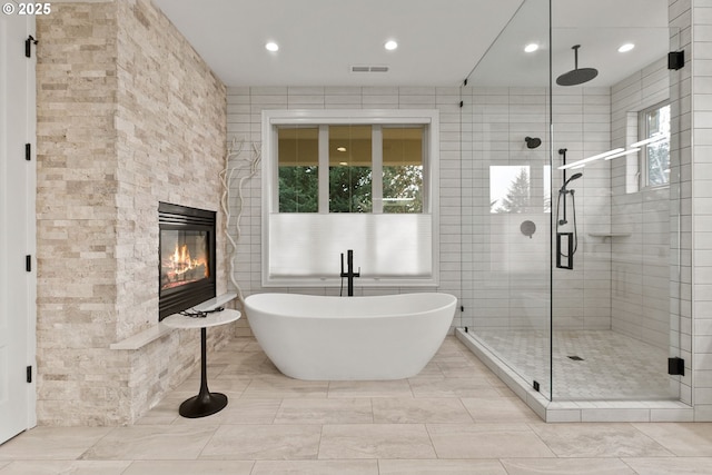 bathroom featuring tile walls, a fireplace, and plus walk in shower