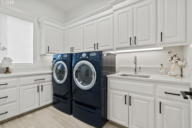 clothes washing area with cabinets, washer and clothes dryer, and sink