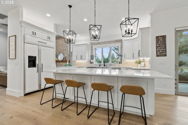 kitchen with hanging light fixtures, paneled refrigerator, decorative backsplash, and a spacious island