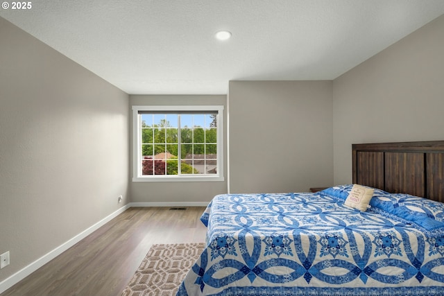 bedroom with wood finished floors, baseboards, and recessed lighting