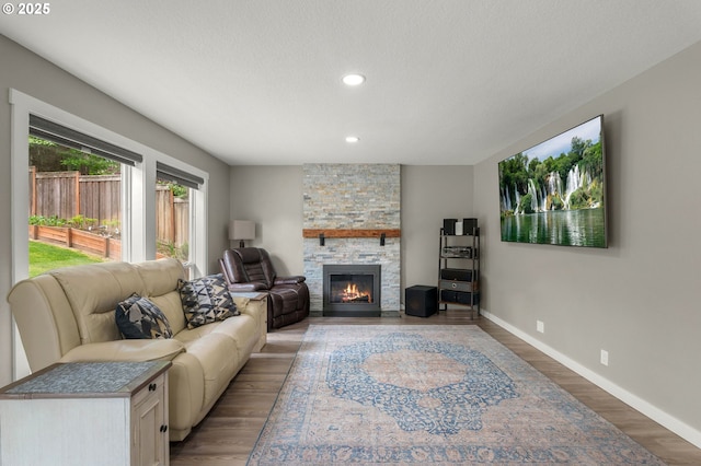 living area with a fireplace, baseboards, light wood-style flooring, recessed lighting, and a textured ceiling