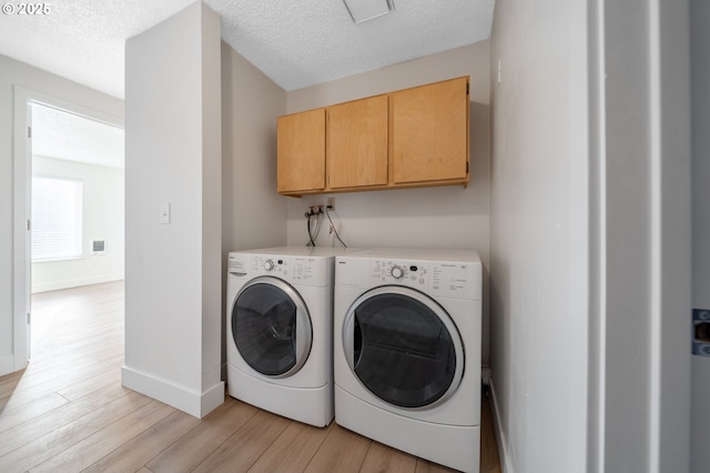 laundry area featuring visible vents, washing machine and dryer, light wood-type flooring, cabinet space, and a textured ceiling