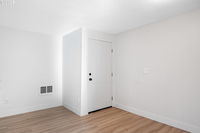 unfurnished room with light wood-type flooring, visible vents, and baseboards