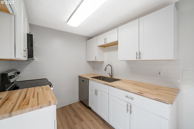 kitchen featuring light wood-style flooring, a sink, stainless steel appliances, white cabinets, and wooden counters