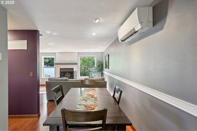 7915 SW Fanno Creek Dr Unit 1, Portland, OR 97224 - dining space featuring an AC wall unit, wood finished floors, baseboards, and a fireplace
