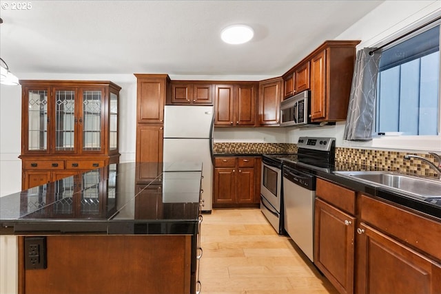 kitchen with appliances with stainless steel finishes, sink, a kitchen island, light wood-type flooring, and pendant lighting