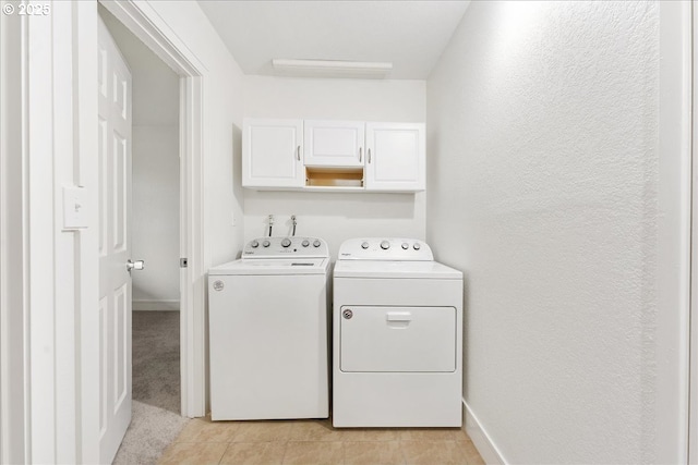 washroom with washer and dryer, cabinets, and light tile patterned flooring