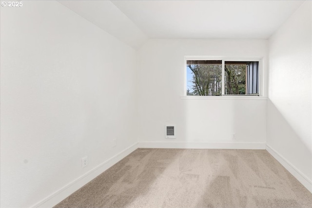 carpeted spare room featuring vaulted ceiling