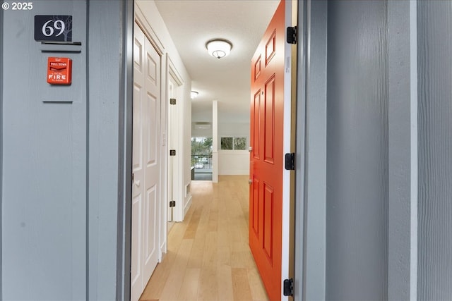 hallway with a textured ceiling and light wood-type flooring