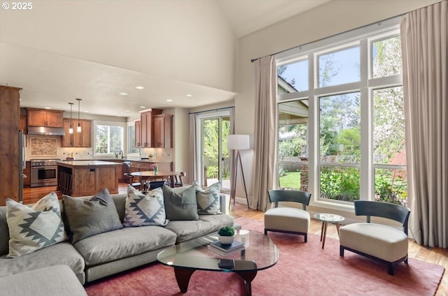 living room with recessed lighting, light wood finished floors, and a towering ceiling