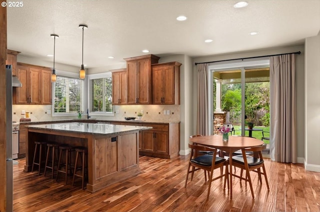 kitchen with backsplash, brown cabinetry, and wood finished floors