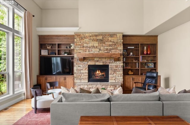 living area featuring visible vents, a stone fireplace, and wood finished floors