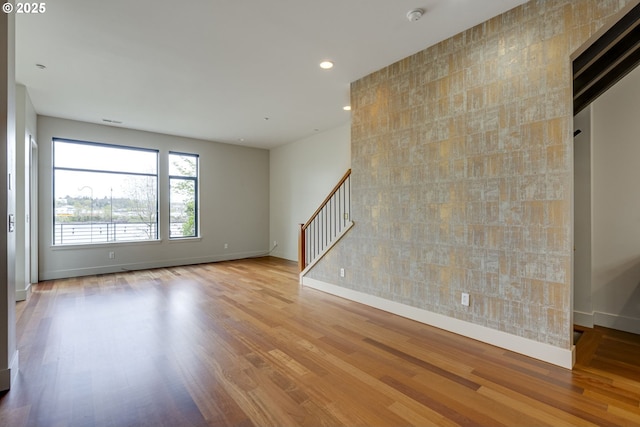 1716 NW Riverscape St, Portland, OR 97209 - empty room with baseboards, an accent wall, recessed lighting, wood finished floors, and stairs