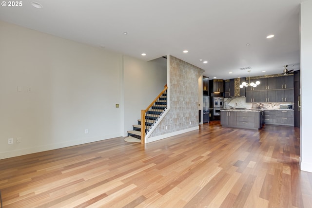 1716 NW Riverscape St, Portland, OR 97209 - unfurnished living room featuring a sink, stairway, recessed lighting, and light wood finished floors