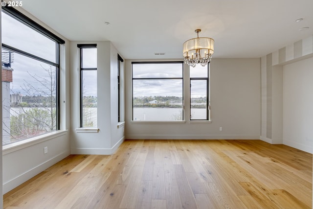 1716 NW Riverscape St, Portland, OR 97209 - unfurnished dining area with a chandelier, light wood finished floors, baseboards, and a healthy amount of sunlight