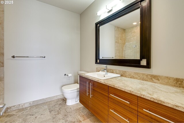 1716 NW Riverscape St, Portland, OR 97209 - full bathroom featuring baseboards, toilet, vanity, tiled shower, and stone finish flooring