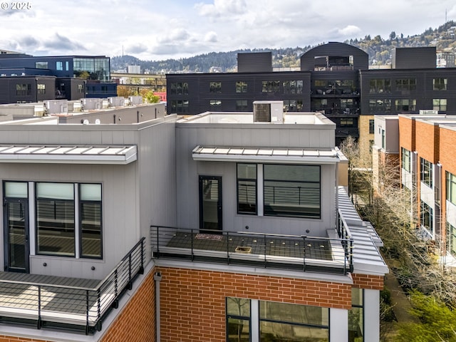 1716 NW Riverscape St, Portland, OR 97209 - rear view of house featuring a balcony, a standing seam roof, metal roof, brick siding, and a mountain view
