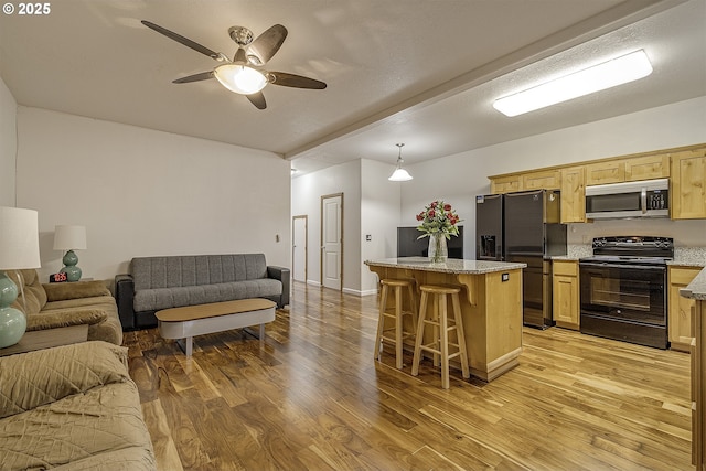 kitchen with a center island, open floor plan, appliances with stainless steel finishes, a kitchen breakfast bar, and light wood-style floors