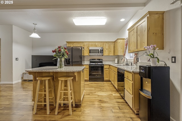 kitchen with black appliances, a center island, light wood-style floors, and a sink