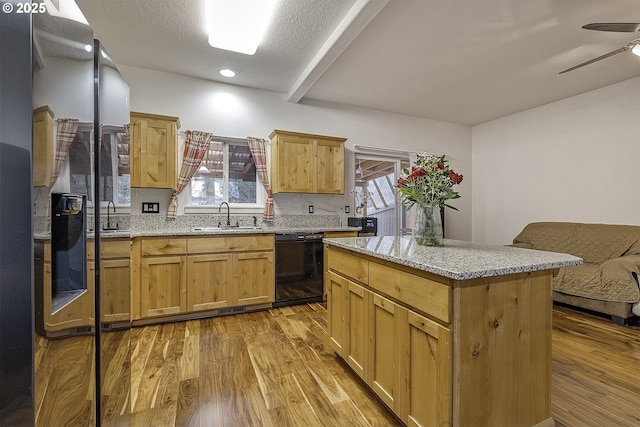 kitchen featuring light stone countertops, dishwasher, wood finished floors, and a sink