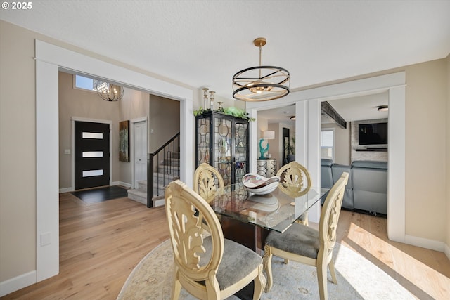 dining space with baseboards, plenty of natural light, light wood-style flooring, and a chandelier