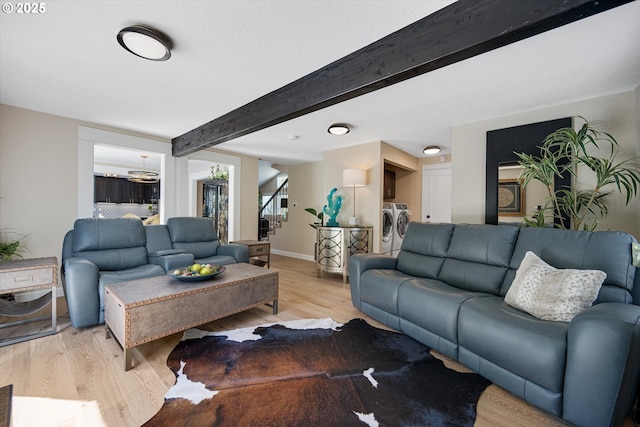 living area with baseboards, beam ceiling, stairs, and light wood-style flooring