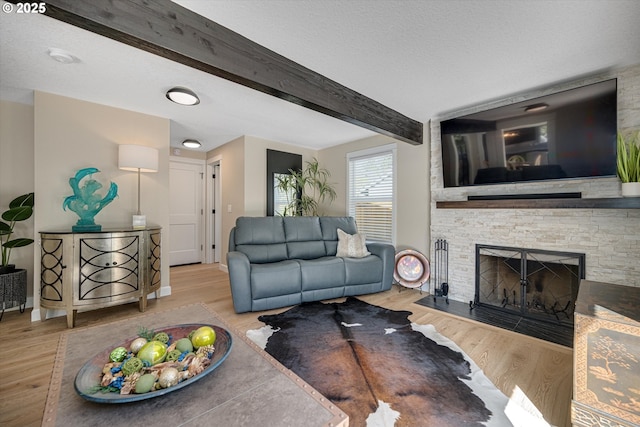 living room with wood finished floors, a fireplace, and beamed ceiling