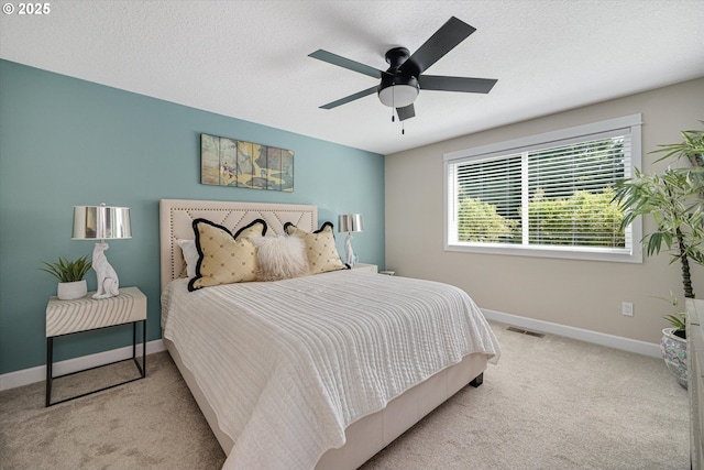 carpeted bedroom featuring a textured ceiling, baseboards, visible vents, and ceiling fan