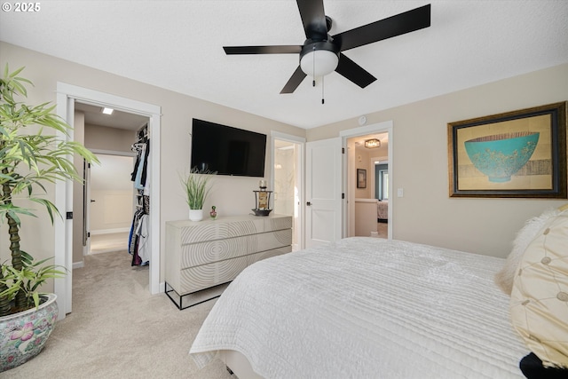 bedroom with a closet, ceiling fan, a spacious closet, and light carpet