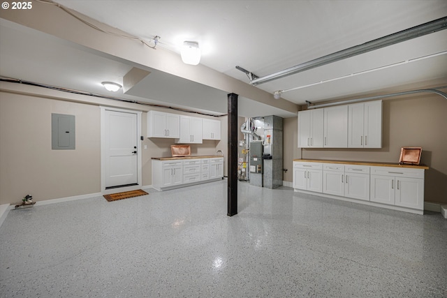 garage featuring heating unit, baseboards, and electric panel