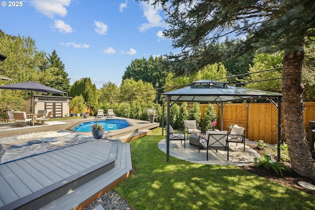 view of swimming pool featuring a lawn, a wooden deck, a gazebo, fence, and a fenced in pool
