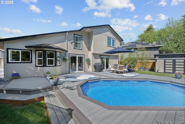 rear view of house with a fenced in pool, a wooden deck, and french doors