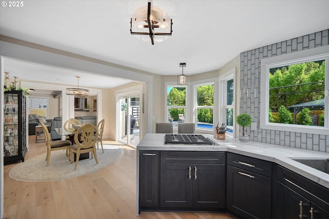 kitchen featuring light wood finished floors, light countertops, a chandelier, a peninsula, and decorative light fixtures