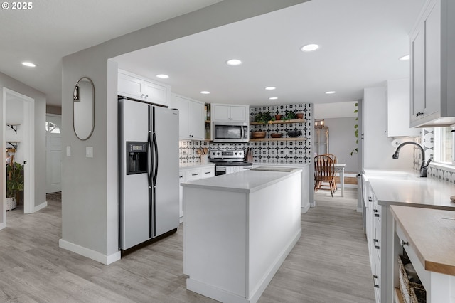 kitchen featuring stainless steel appliances, white cabinets, light countertops, open shelves, and tasteful backsplash