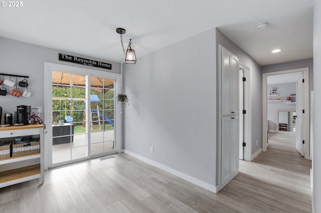 interior space with baseboards, visible vents, and light wood finished floors