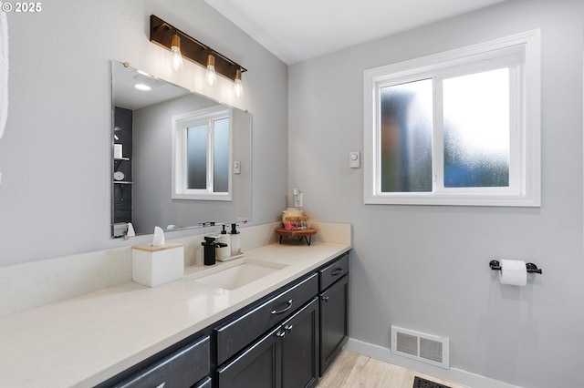 bathroom featuring baseboards, visible vents, wood finished floors, and vanity