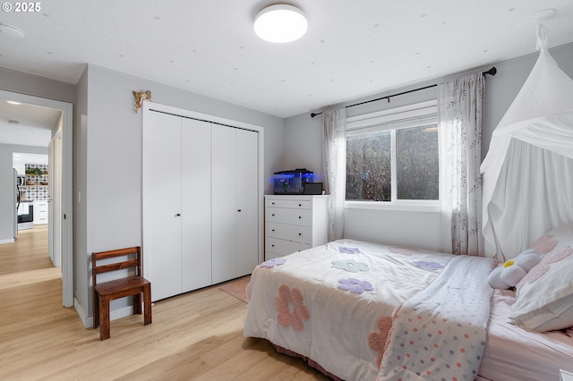 bedroom with light wood finished floors and a closet