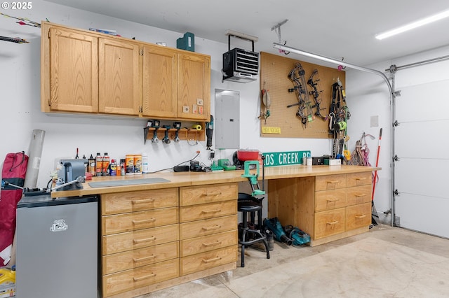 garage with a workshop area, fridge, and electric panel