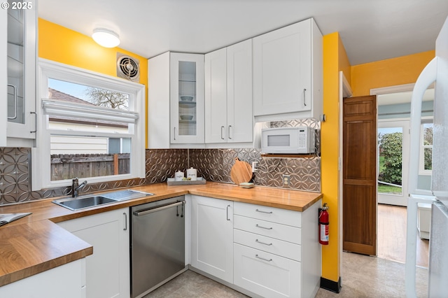 kitchen featuring a sink, white microwave, butcher block countertops, and dishwasher